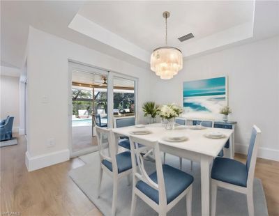 Dining room featuring an inviting chandelier, light hardwood / wood-style floors, and a tray ceiling | Image 2