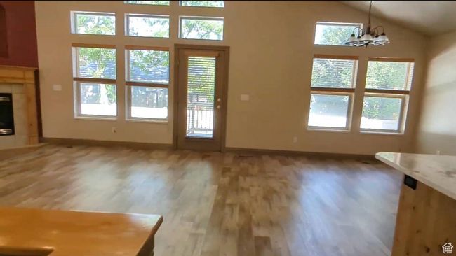 Unfurnished living room featuring light wood-type flooring, healthy amount of natural light, baseboards, and lofted ceiling | Image 17