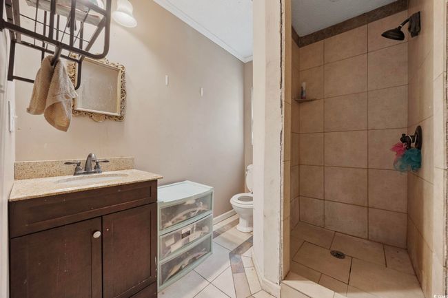 Bathroom with a tile shower, vanity, crown molding, and tile patterned flooring | Image 6