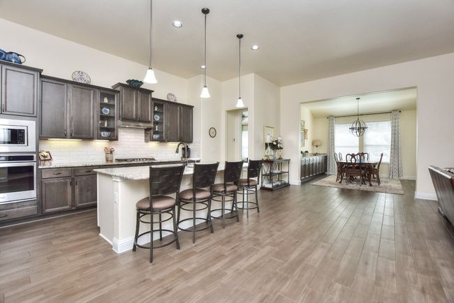 Kitchen with a kitchen bar, tasteful backsplash, wood finished floors, stainless steel appliances, and dark brown cabinets | Image 4