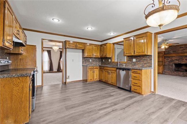 Kitchen with light hardwood / wood-style flooring, a brick fireplace, ceiling fan, tasteful backsplash, and stainless steel appliances | Image 13