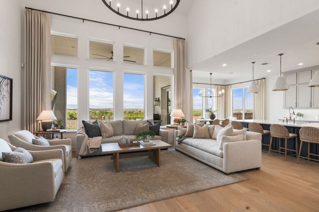 Living room with a chandelier, light wood-type flooring, a towering ceiling, and recessed lighting | Image 5