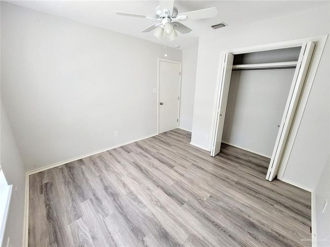 Unfurnished bedroom featuring wood finished floors, a closet, and a ceiling fan | Image 8