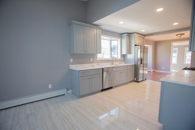 Kitchen featuring gray cabinetry, sink, appliances with stainless steel finishes, and a baseboard radiator | Image 13