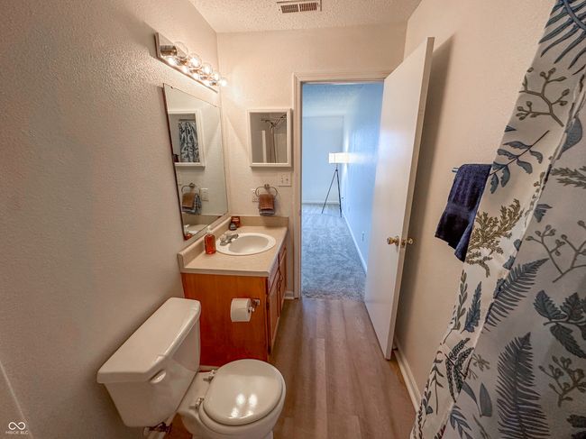 bathroom with vanity, visible vents, toilet, wood finished floors, and a textured wall | Image 22