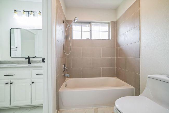 Bathroom with toilet, vanity, shower combination, and marble look tile flooring | Image 28