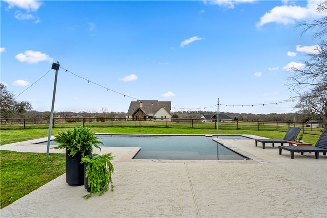 View of pool featuring a patio area, fence, and a yard | Image 45
