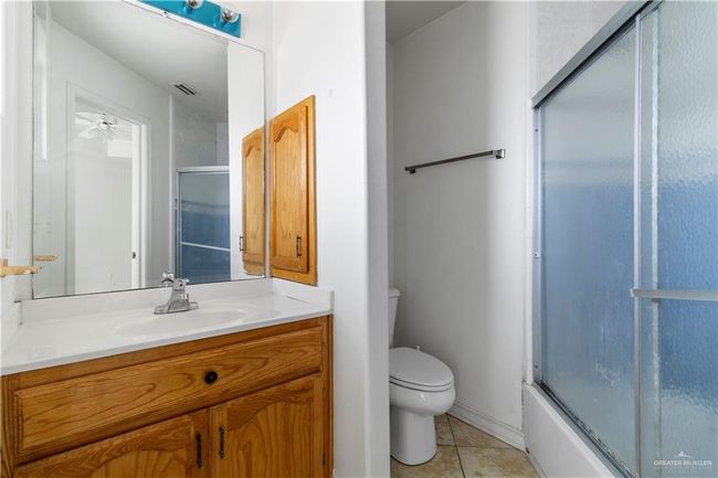 Full bathroom with vanity, tile patterned flooring, combined bath / shower with glass door, and ceiling fan | Image 13