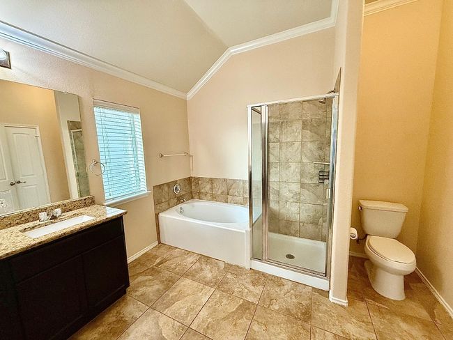 Full bathroom featuring crown molding, vaulted ceiling, a bath, vanity, and a stall shower | Image 12