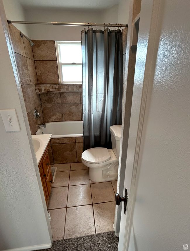 Bathroom featuring toilet, tiled shower / bath, tile patterned flooring, and vanity | Image 7