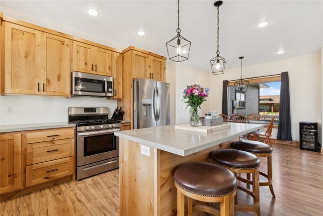 Kitchen with a kitchen bar, a center island, appliances with stainless steel finishes, and light wood finished floors | Image 21