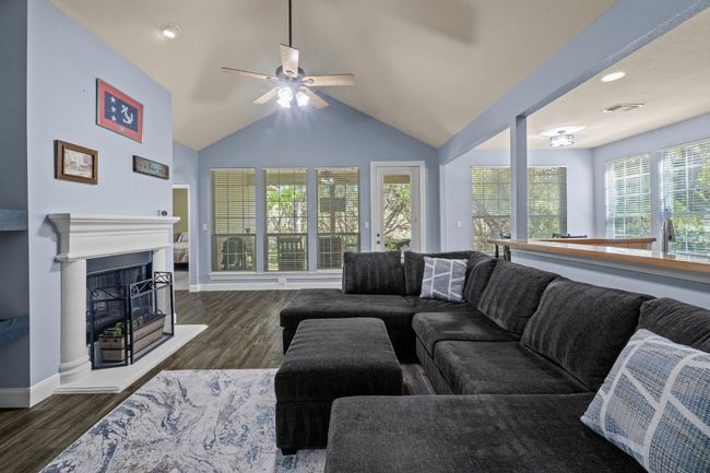 Living room with , a ceiling fan, a fireplace with raised hearth, and wood finished floors | Image 6