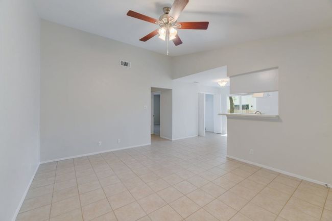 Unfurnished room featuring a ceiling fan, light tile patterned floors, lofted ceiling, and baseboards | Image 12