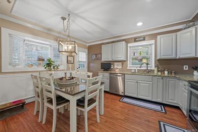 Kitchen with sink, appliances with stainless steel finishes, white cabinetry, and light hardwood / wood-style floors | Image 2