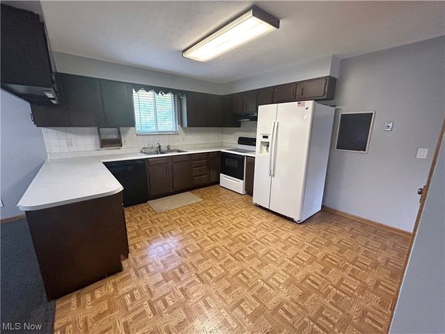 Kitchen with backsplash, white appliances, sink, and light parquet flooring | Image 8