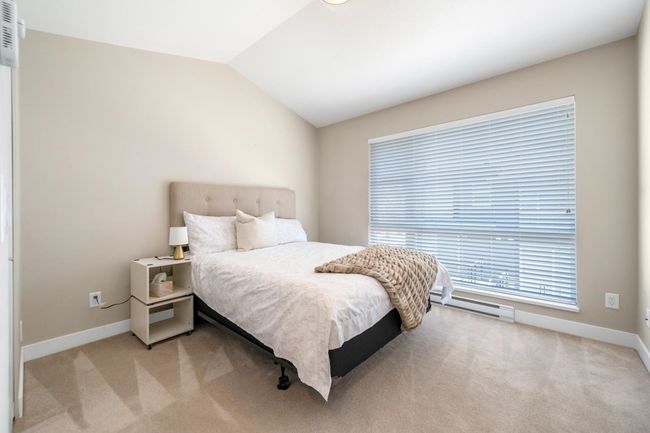 Bedroom with baseboards, light carpet, lofted ceiling, and a baseboard radiator | Image 11