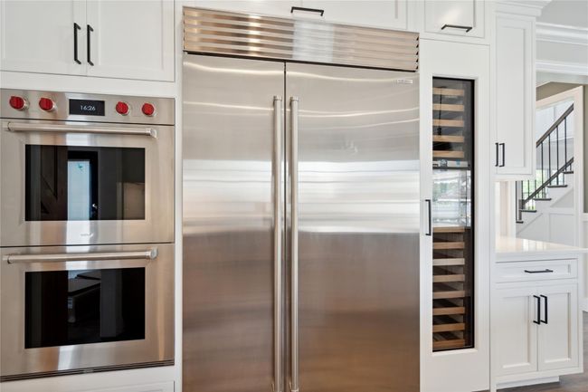 Kitchen with appliances with stainless steel finishes, white cabinets, and light countertops | Image 11
