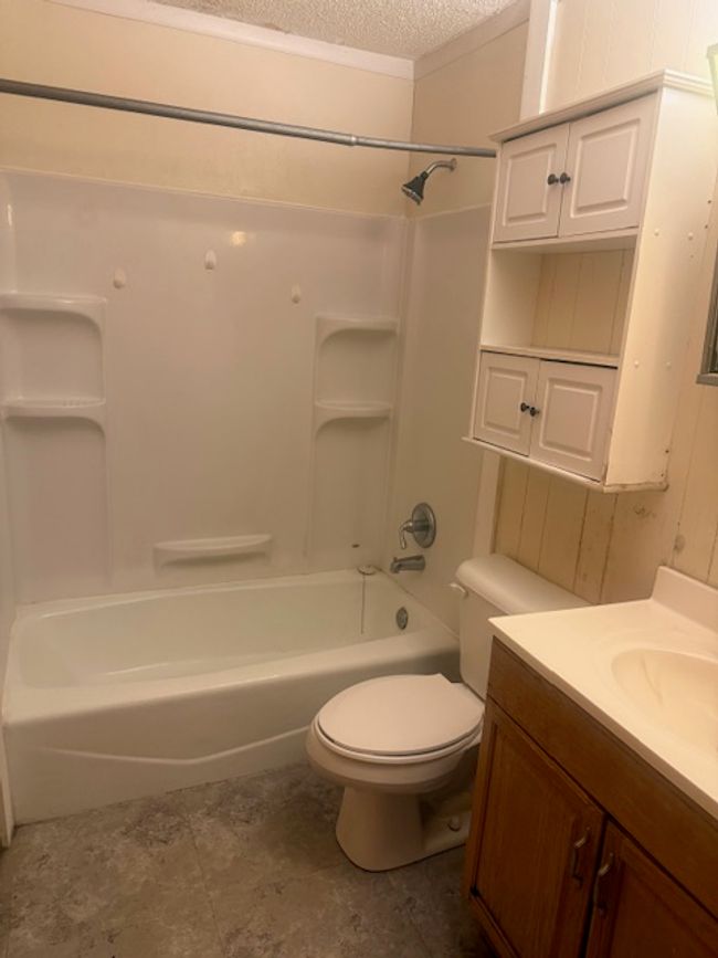 Full bathroom featuring vanity, a textured ceiling, shower / tub combination | Image 6