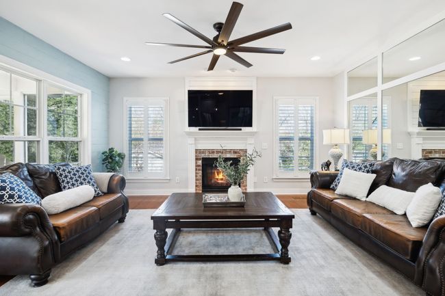 Warm and welcoming, this space features brick fireplace, and classic plantation shutters. | Image 14