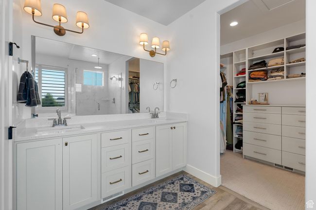 Primary suite bathroom with a shower stall, a spacious closet, double vanity, and wood finished floors | Image 15