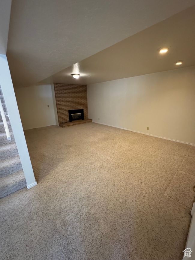 Unfurnished living room featuring carpet flooring and a brick fireplace | Image 13