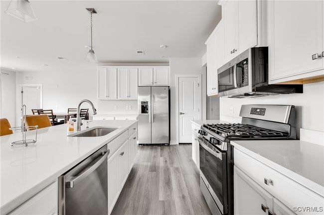 Kitchen with appliances with stainless steel finishes, light wood-type flooring, light countertops, and white cabinetry | Image 16