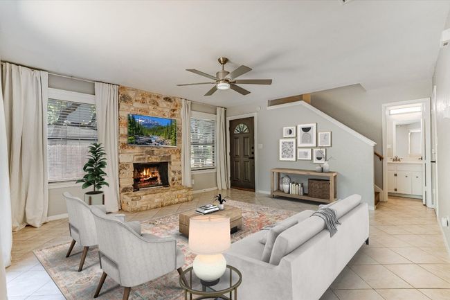 Living room featuring light tile patterned flooring, ceiling fan, stairs, a stone fireplace, and baseboards | Image 4