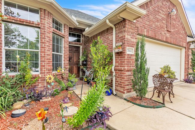 Property entrance with brick siding, a garage, roof with shingles, and concrete driveway | Image 6