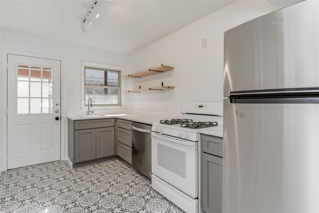 Kitchen featuring stainless steel appliances, gray cabinetry, a sink, rail lighting, and light countertops | Image 21