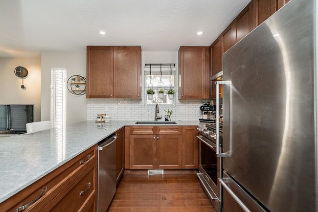 Kitchen with visible vents, a sink, appliances with stainless steel finishes, dark wood finished floors, and decorative backsplash | Image 5