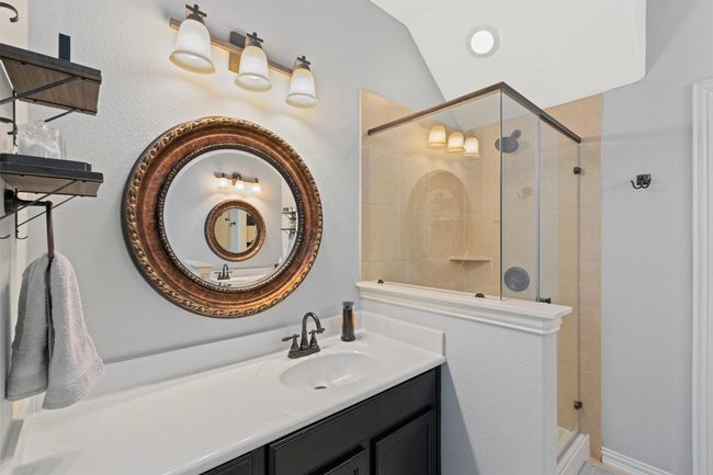 Bathroom featuring a stall shower, vanity, and lofted ceiling | Image 18