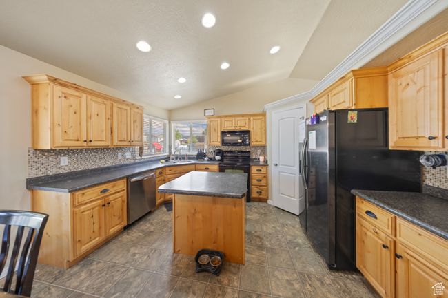 Kitchen with black appliances, lofted ceiling, a center island, dark countertops, and decorative backsplash | Image 8