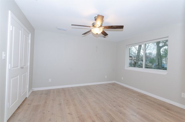 Primary bedroom with visible vents, ceiling fan, baseboards, and light wood-style floors | Image 8