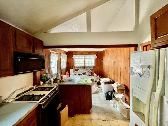 Kitchen featuring vaulted ceiling, gas stove, a peninsula, light countertops, and fridge | Image 6