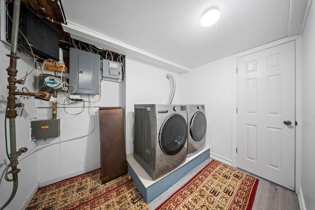 Washroom with electric panel, wood finished floors, washing machine and dryer, baseboards, and laundry area | Image 21