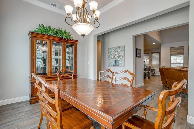 Dining space featuring crown molding, light wood-style flooring, and a chandelier | Image 11
