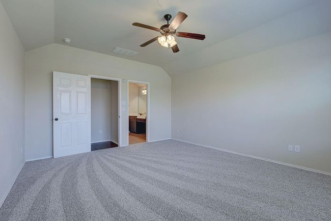 Unfurnished bedroom with lofted ceiling, carpet floors, baseboards, ceiling fan, and ensuite bath | Image 11