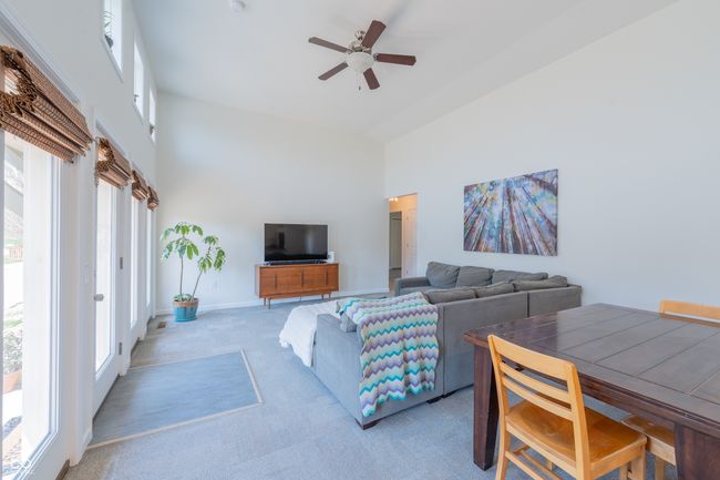 living room featuring carpet flooring, a high ceiling, a ceiling fan, and baseboards | Image 12