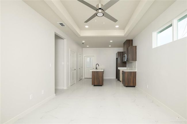 Unfurnished living room with light marble finish floors, baseboards, ceiling fan, recessed lighting, and a sink | Image 4