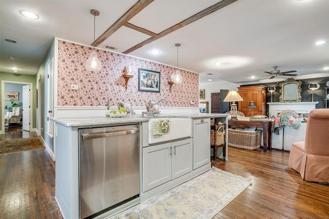 Kitchen with stainless steel dishwasher, open floor plan, wallpapered walls, and dark wood finished floors | Image 9