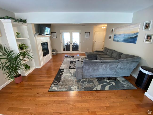 Living room featuring wood finished floors, french doors, a glass covered fireplace, and baseboards | Image 6