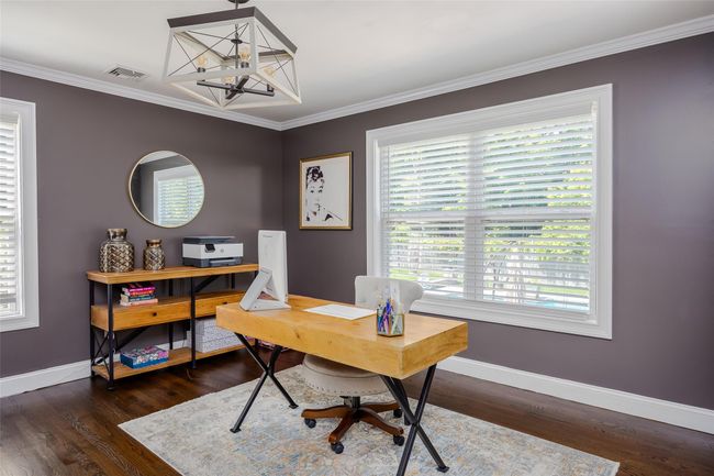 Office space with dark wood finished floors, crown molding, and a chandelier | Image 12