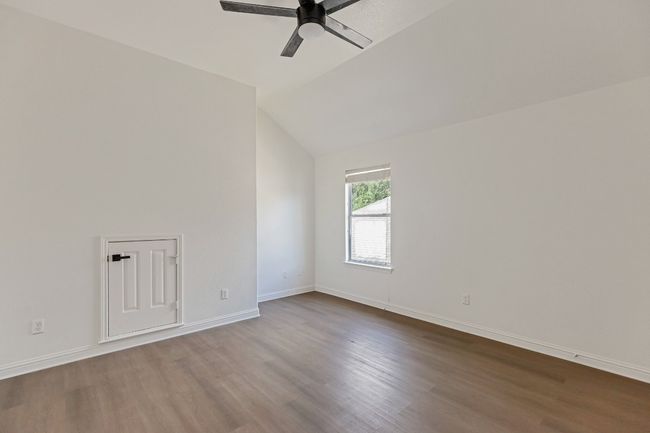 Empty room with wood finished floors, a ceiling fan, and vaulted ceiling | Image 20