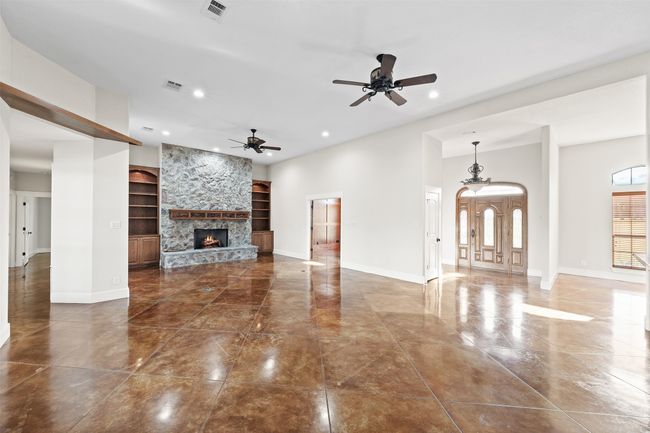 Unfurnished living room with built in features, ceiling fan, baseboards, a stone fireplace, and recessed lighting | Image 5
