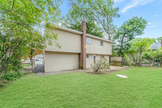 Rear view of house with a chimney, fence, a gate, and a yard | Image 21