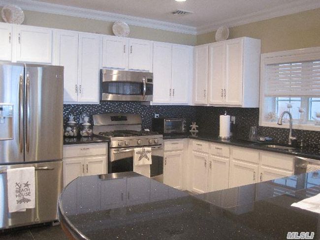 Kitchen featuring stainless steel appliances, a sink, white cabinets, and crown molding | Image 5