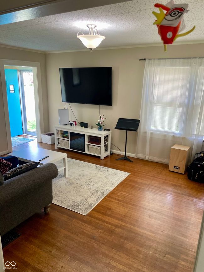 living room with wood finished floors, crown molding, and baseboards | Image 6