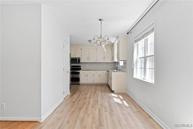 Kitchen featuring stainless steel appliances, a chandelier, light wood finished floors, tasteful backsplash, and light countertops | Image 11