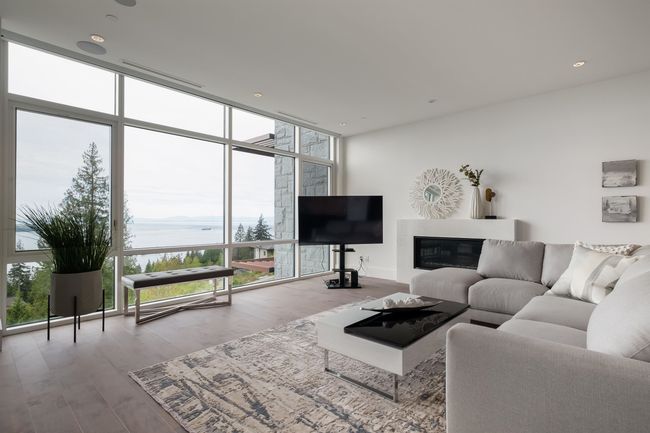 Living area with a wall of windows, wood finished floors, and a glass covered fireplace | Image 9