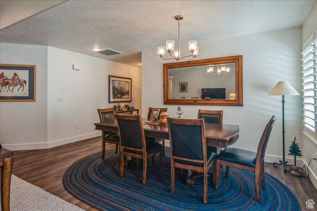 Dining area with a chandelier, dark wood-style floors, baseboards, and a textured ceiling | Image 12
